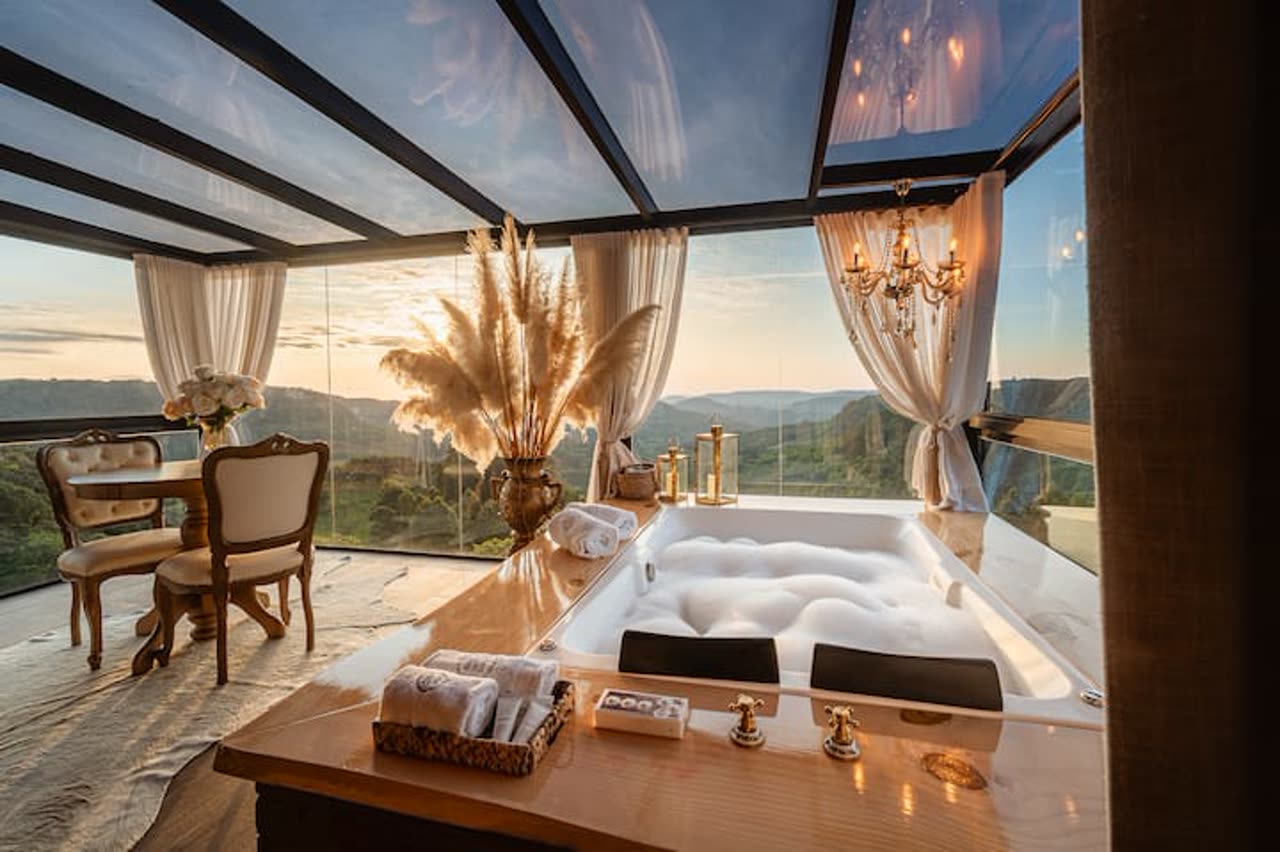 Hidromassagem sob teto de vidro com vista para o vale ao entardecer