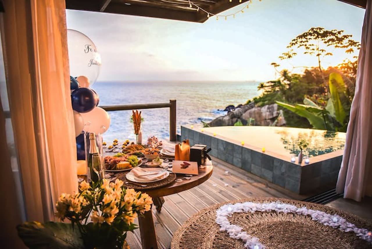 Deck com piscina de borda infinita sobre o mar, ao pôr do sol